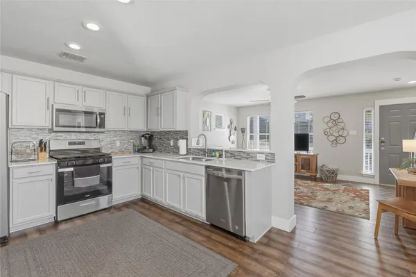 a kitchen with stainless steel appliances granite countertop a stove top oven a sink dishwasher and a refrigerator