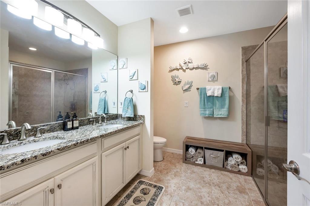14940 Edgewater Circle Naples, FL 34114 - Photo 19 of 39 a bathroom with a granite countertop sink a toilet and a mirror