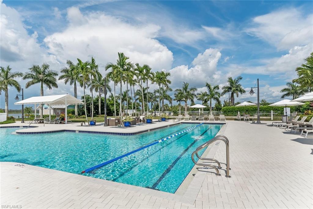 14940 Edgewater Circle Naples, FL 34114 - Photo 30 of 39 a view of a swimming pool with lawn chairs under an umbrella