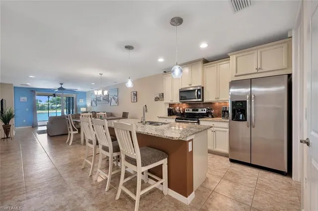 a kitchen with stainless steel appliances granite countertop a refrigerator a stove a sink a table and chairs