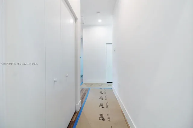 a view of a hallway with wooden floor and a bathroom