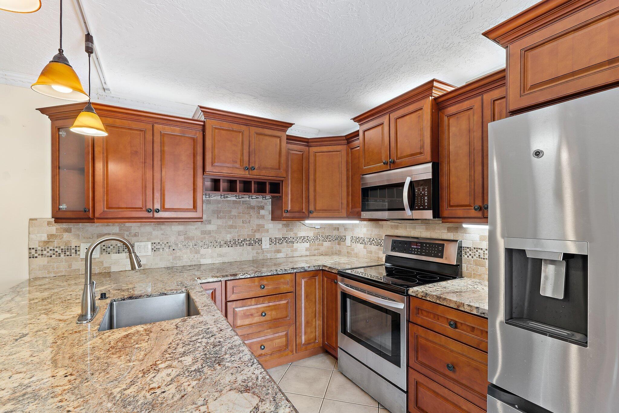 1514 15th Court Jupiter, FL 33477 - Photo 11 of 25 a kitchen with stainless steel appliances granite countertop a sink stove and refrigerator
