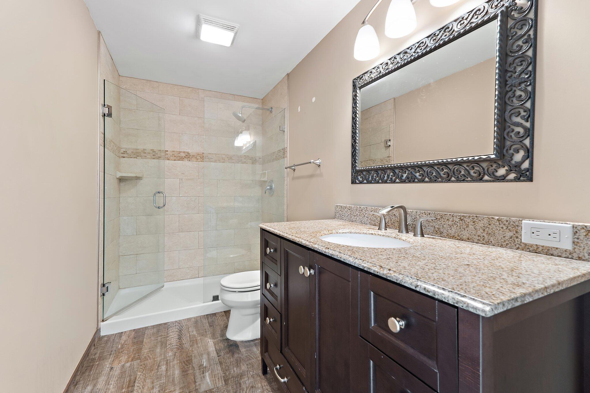 1514 15th Court Jupiter, FL 33477 - Photo 21 of 25 a bathroom with a granite countertop sink a toilet and a mirror