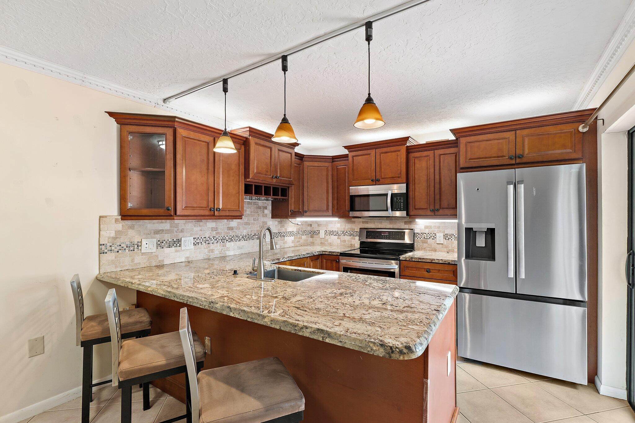 1514 15th Court Jupiter, FL 33477 - Photo 10 of 25 a kitchen with stainless steel appliances granite countertop a sink refrigerator and microwave