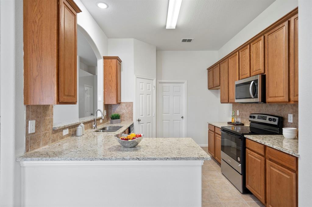 613 Hummingbird Trail Crowley, TX 76036 - Photo 12 of 37 a kitchen with stainless steel appliances granite countertop a sink stove and cabinets