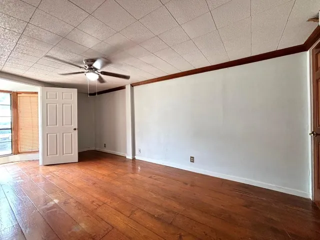 an empty room with wooden floor and windows with curtains