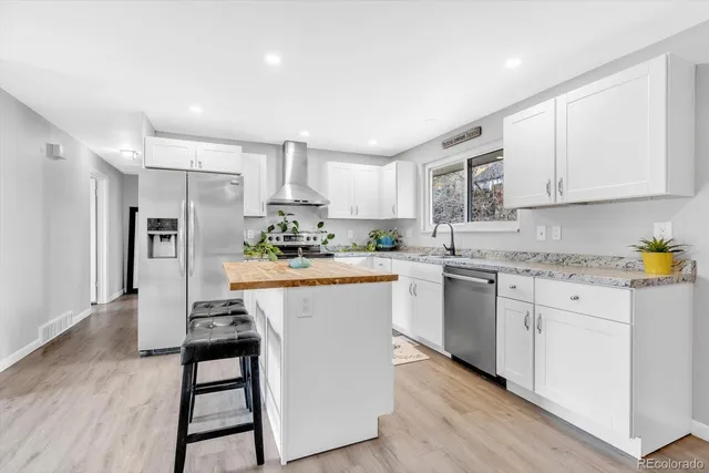 a kitchen with stainless steel appliances granite countertop a refrigerator sink and white cabinets