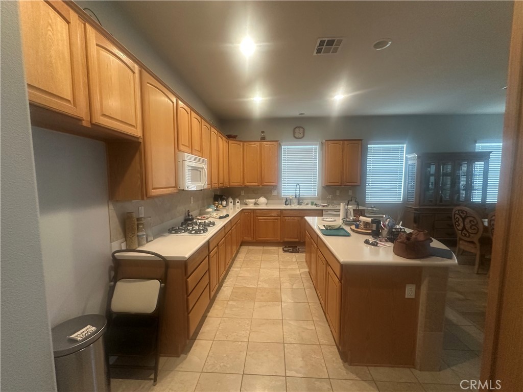 1185 Lantana Road Beaumont, CA 92223 - Photo 6 of 36 a large white kitchen with a sink a stove and a refrigerator