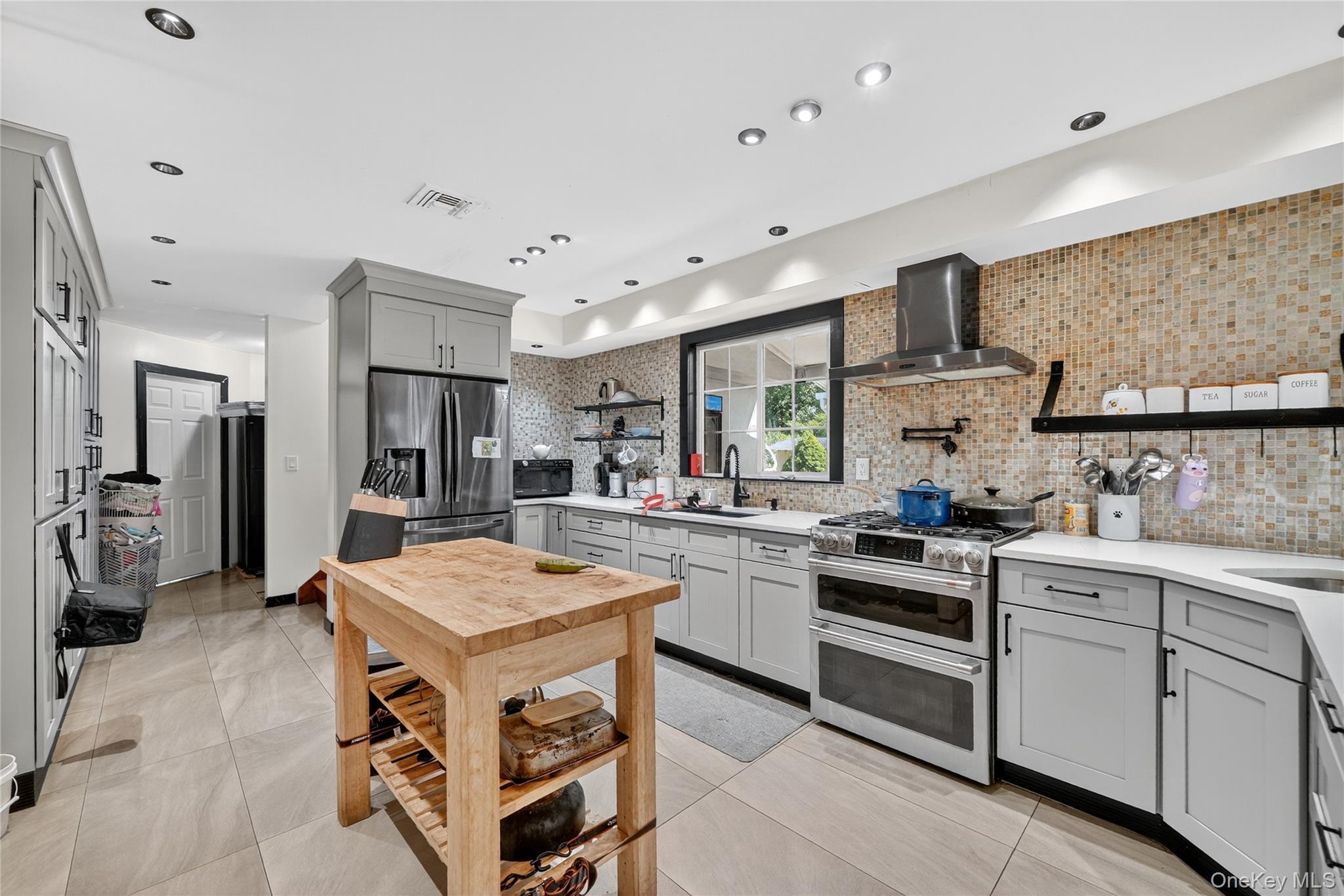 306 South Pascack Road Nanuet, NY 10954 - Photo 16 of 48 Kitchen with gray cabinetry, open shelves, appliances with stainless steel finishes, decorative backsplash, and wall chimney range hood