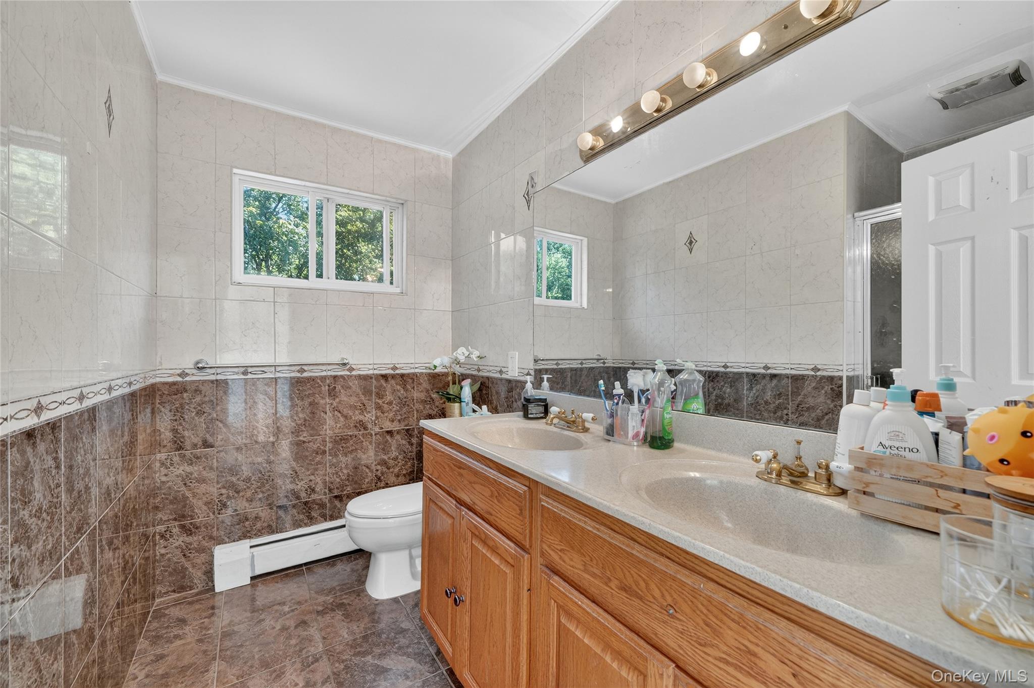 306 South Pascack Road Nanuet, NY 10954 - Photo 23 of 48 Bathroom with tile walls, double vanity, ornamental molding, a baseboard heating unit, and a shower stall