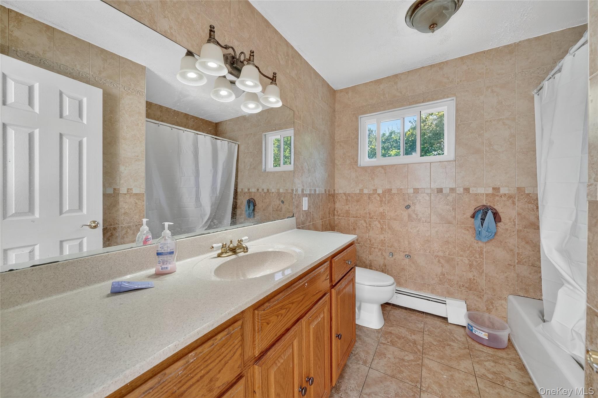306 South Pascack Road Nanuet, NY 10954 - Photo 27 of 48 Bathroom featuring tile walls, vanity, light tile patterned flooring, a baseboard heating unit, and shower / tub combo with curtain