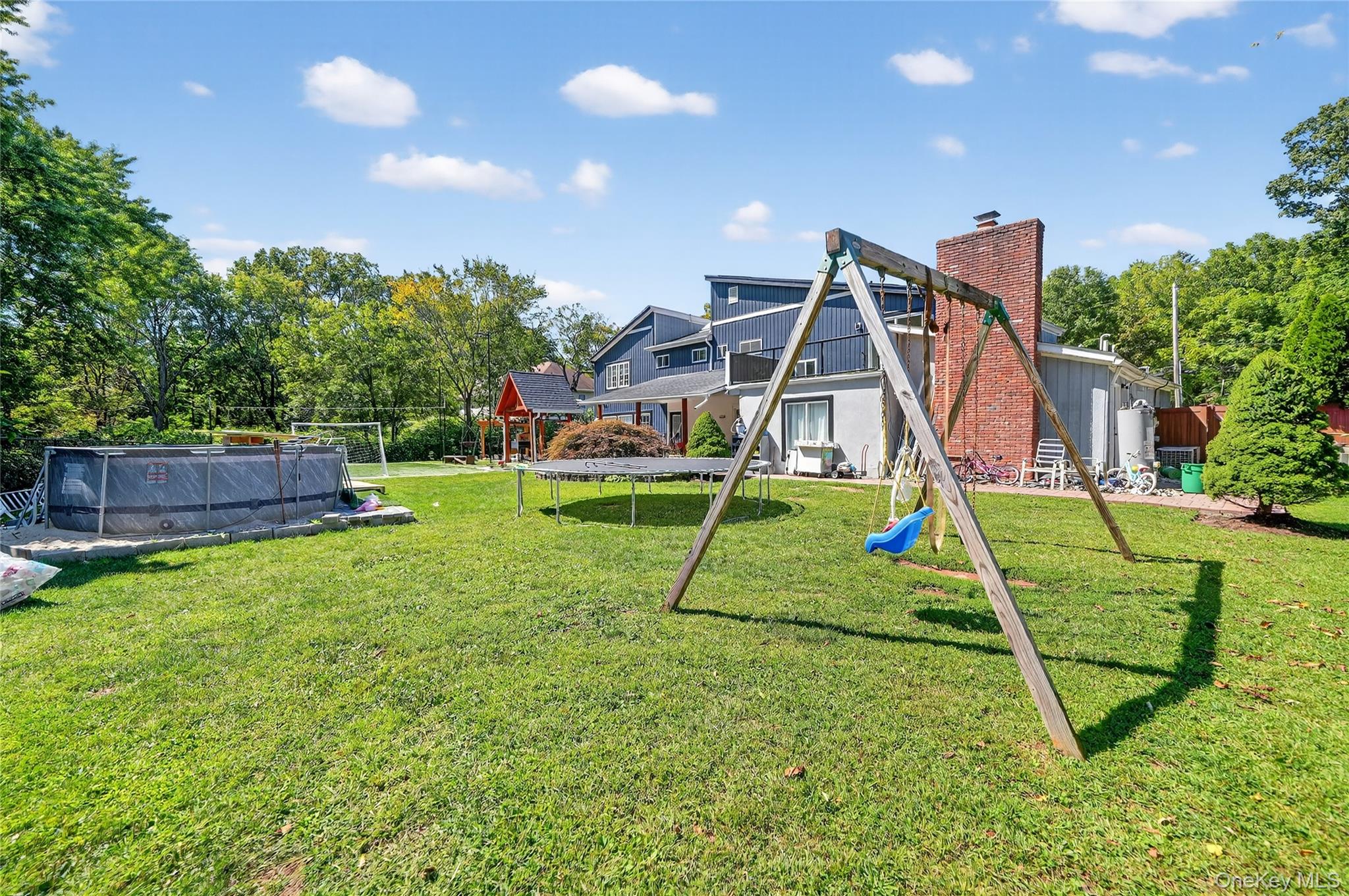 306 South Pascack Road Nanuet, NY 10954 - Photo 41 of 48 Rear view of property featuring a playground, an outdoor pool, a trampoline, view of scattered trees, and a chimney