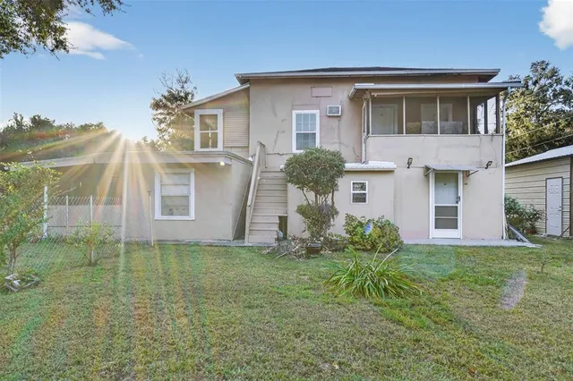 a view of a house with a big yard plants and large trees