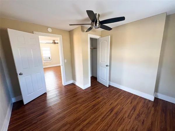an empty room with wooden floor and a ceiling fan