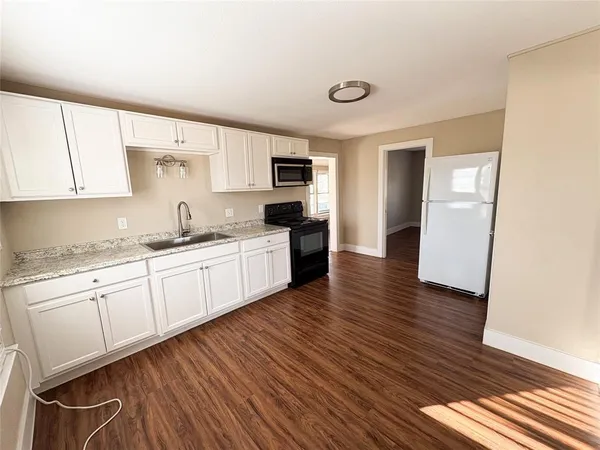 a kitchen with granite countertop wooden floors a sink and cabinets