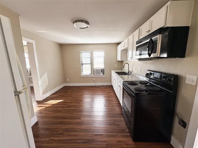 a kitchen with stainless steel appliances a refrigerator a stove a microwave cabinets and a window