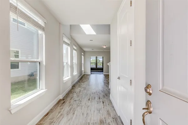 a view of a kitchen and an empty room with wooden floor and a window