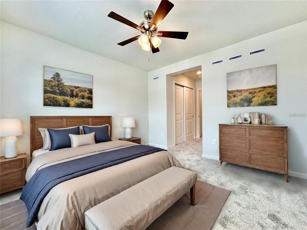 4652 Sparkling Shell Avenue Kissimmee, FL 34746 - Photo 12 of 35 a bedroom with a large bed a flat screen tv and couches