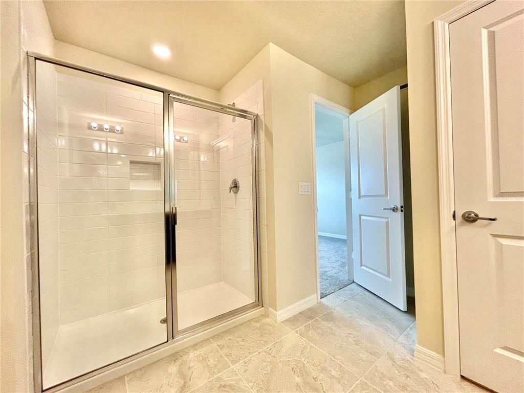 4652 Sparkling Shell Avenue Kissimmee, FL 34746 - Photo 21 of 35 a bathroom with a glass shower door