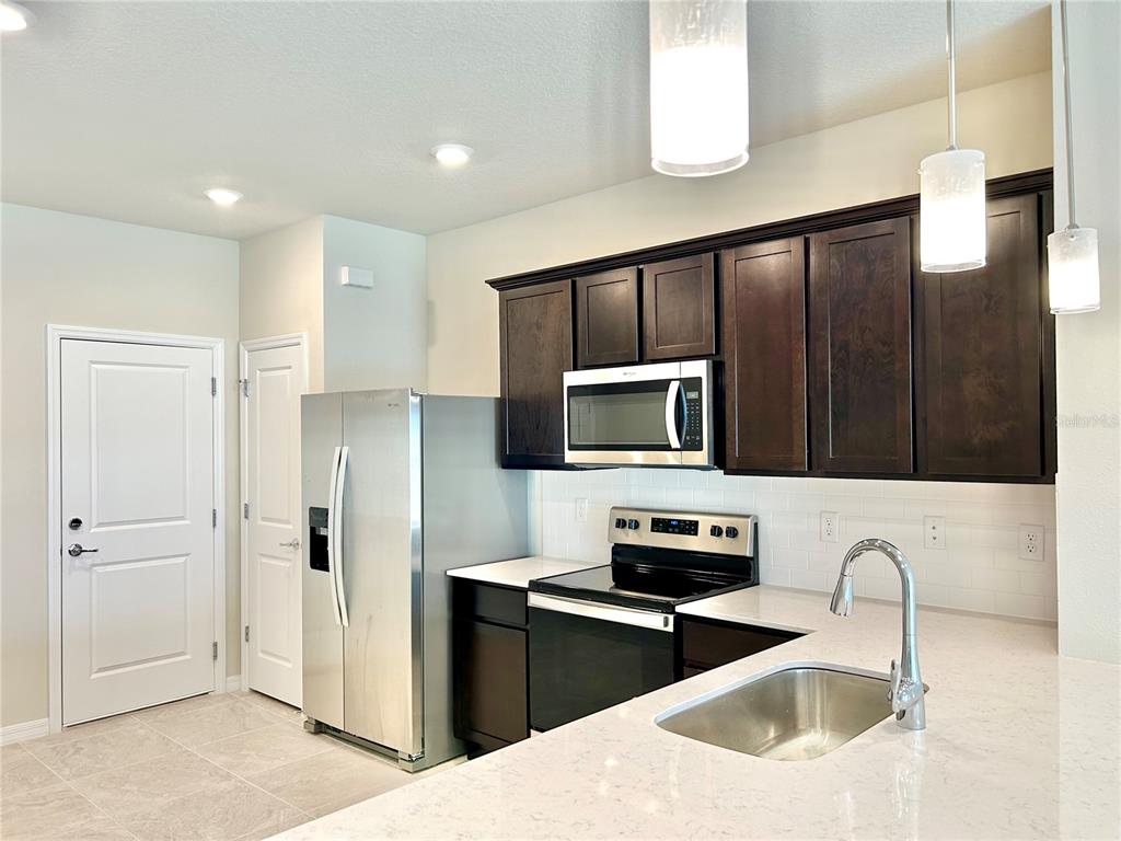 4652 Sparkling Shell Avenue Kissimmee, FL 34746 - Photo 5 of 35 a kitchen with granite countertop a refrigerator and a sink