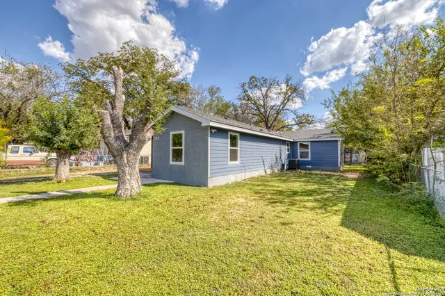 a view of a house with a yard and large tree