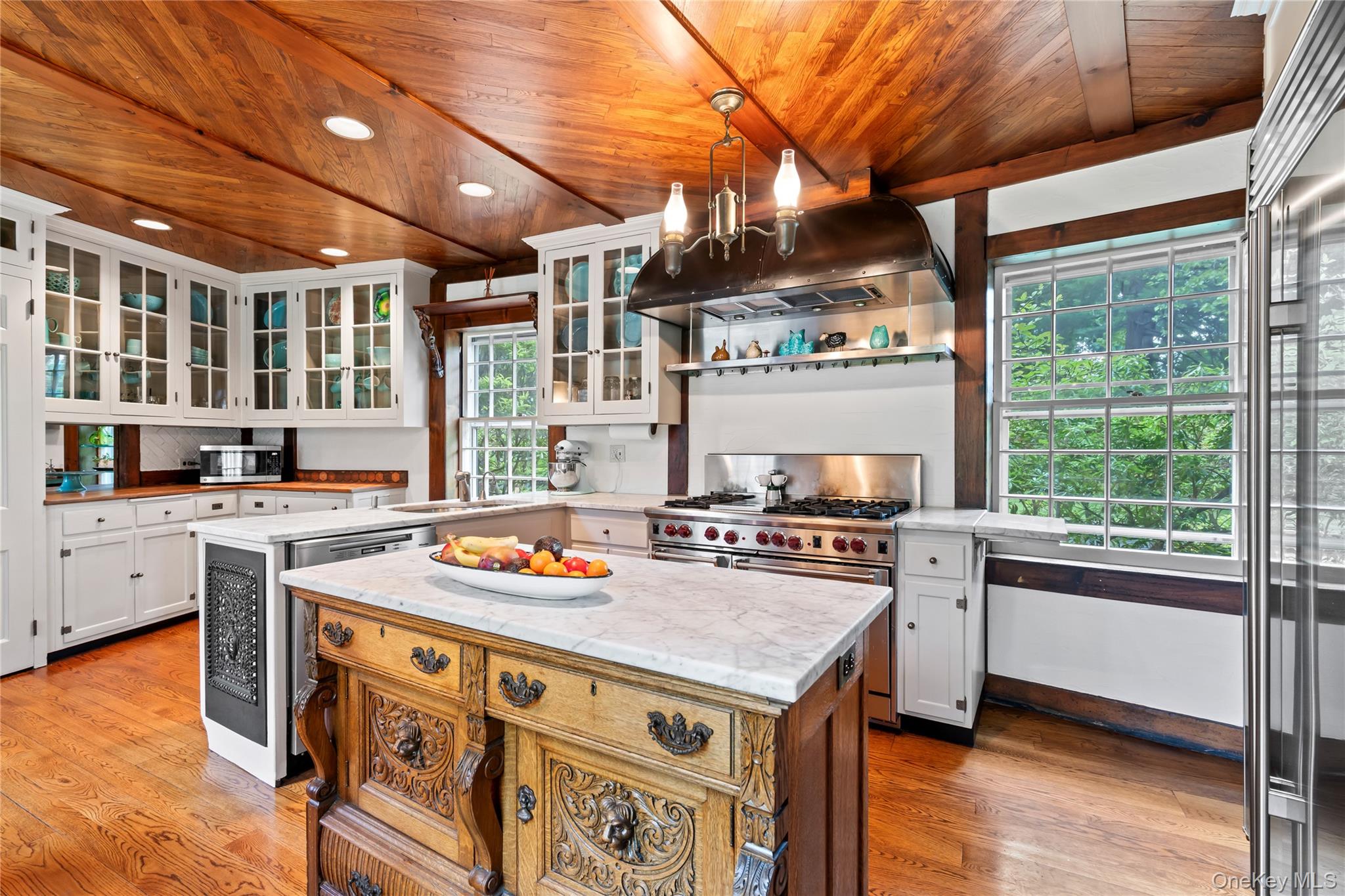 88 Wheatley Road Old Westbury, NY 11568 - Photo 18 of 40 Kitchen with hanging light fixtures, white cabinets, a center island, glass insert cabinets, and under cabinet range hood