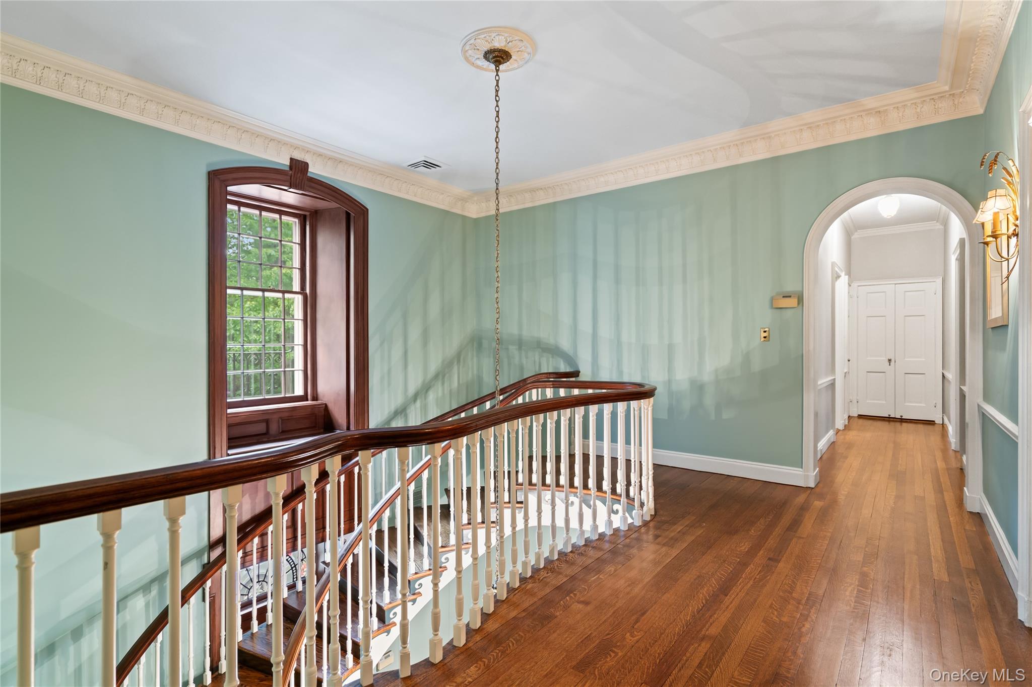88 Wheatley Road Old Westbury, NY 11568 - Photo 23 of 40 Stairway featuring hardwood / wood-style flooring, ornamental molding, and arched walkways