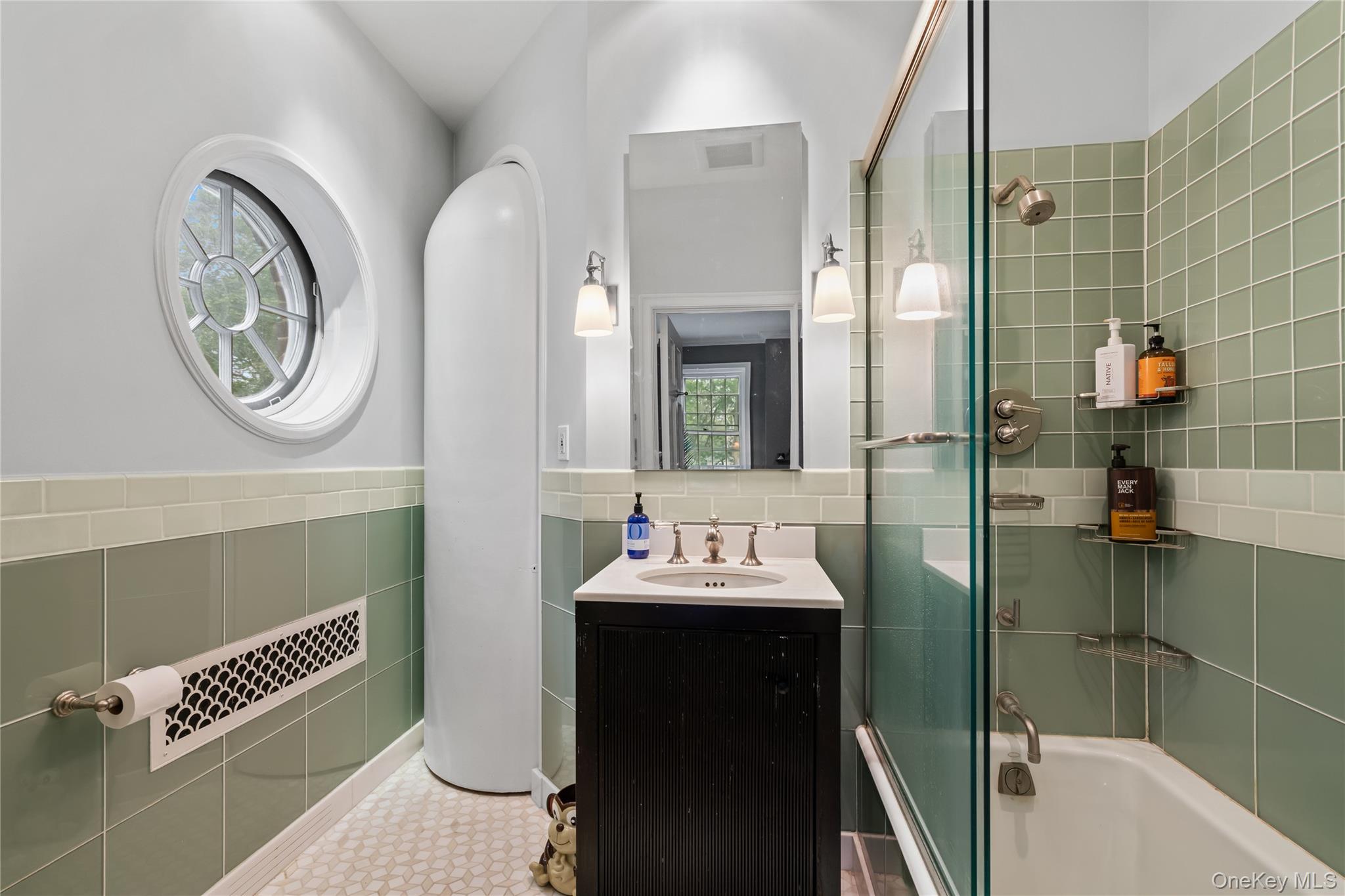88 Wheatley Road Old Westbury, NY 11568 - Photo 28 of 40 Full bathroom featuring bath / shower combo with glass door, vanity, tile walls, and wainscoting