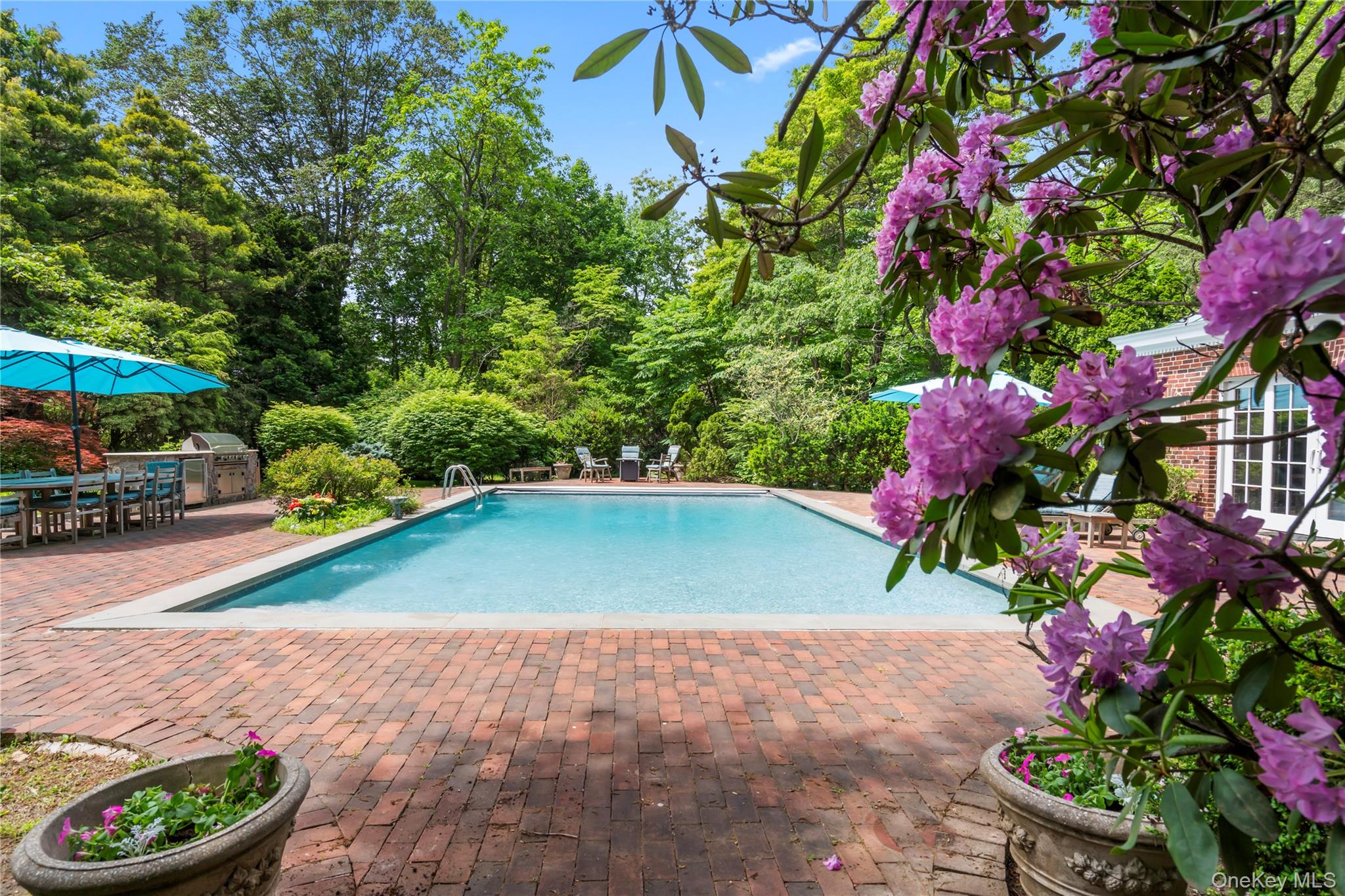 88 Wheatley Road Old Westbury, NY 11568 - Photo 36 of 40 Swimming pool with a patio area, outdoor dining space, and view of wooded area