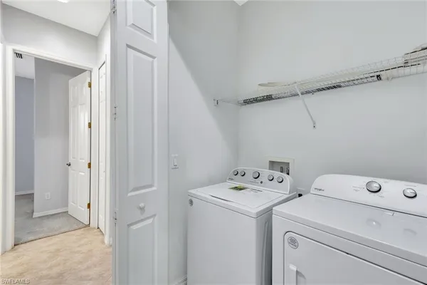 a view of washer and dryer with bathroom in the background