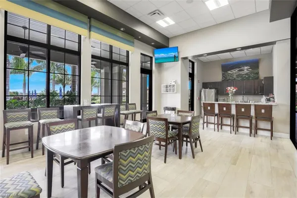 a dining hall with furniture a large window and kitchen view