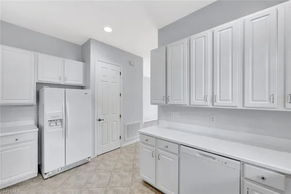 a kitchen with white cabinets and a refrigerator