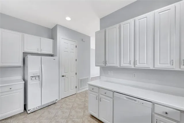 a kitchen with white cabinets and a refrigerator