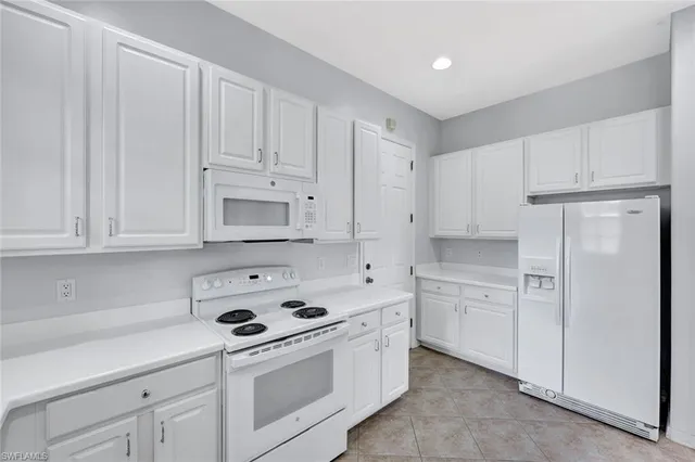 a kitchen with white cabinets and white appliances