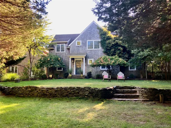 a view of a big house with a big yard and large trees