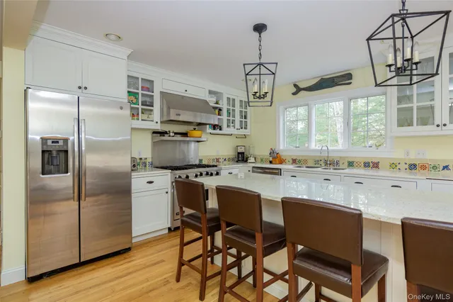 a kitchen with stainless steel appliances kitchen island granite countertop a refrigerator a stove a sink dishwasher a dining table and chairs with wooden floor