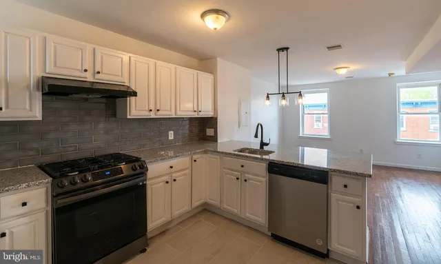 a kitchen with granite countertop a sink a stove and cabinets