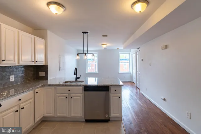 a kitchen with white cabinets and sink