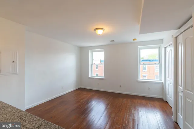 an empty room with wooden floor and windows