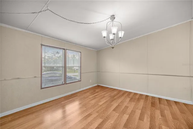a view of an empty room with window and a kitchen