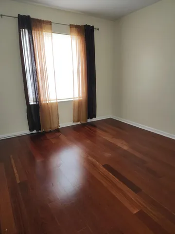 an empty room with wooden floor and windows with curtains