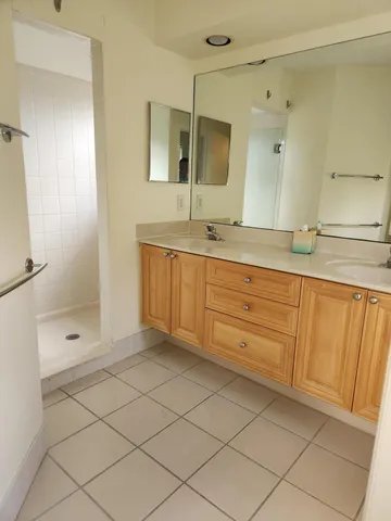 a spacious bathroom with a mirror a shower and a sink