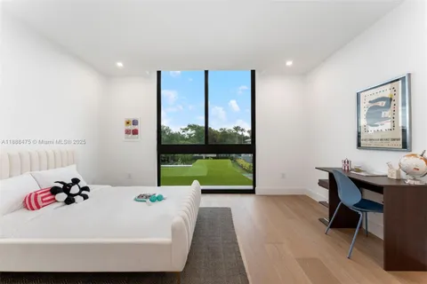 a bedroom with a bed a standing fan and a window