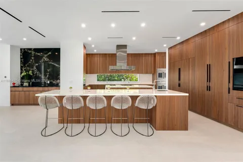 a kitchen with granite countertop lots of wooden cabinets stainless steel appliances a large window and a fireplace