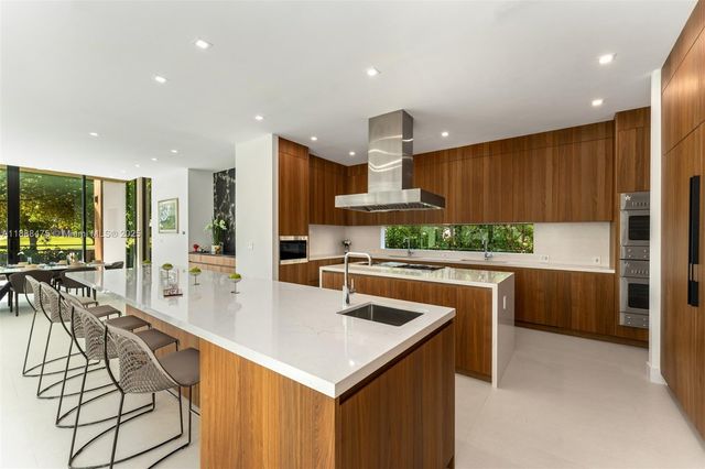 a kitchen with stainless steel appliances kitchen island granite countertop a sink a stove and a refrigerator
