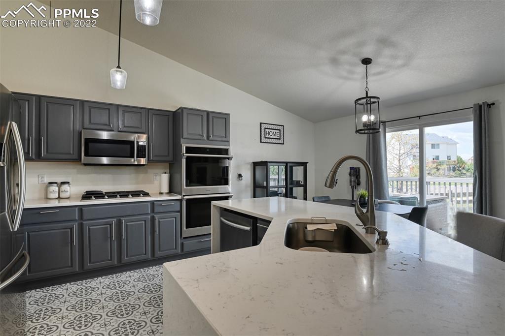 8820 Oakmont Road Peyton, CO 80831 - Photo 32 of 50 a kitchen with stainless steel appliances granite countertop a sink dishwasher a stove top oven a refrigerator with island and chairs