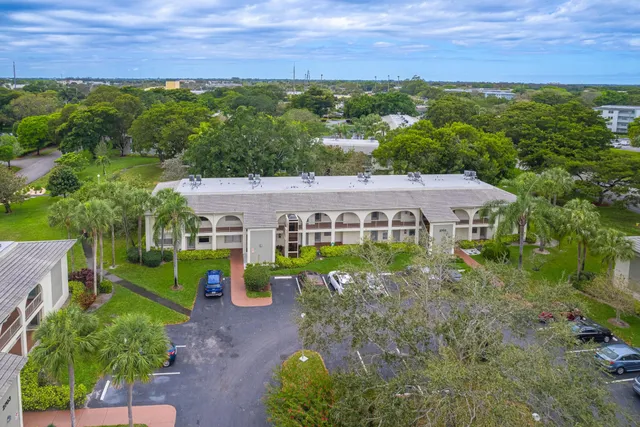 a view of a house with a big yard plants and large trees