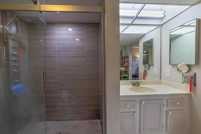 a bathroom with a sink shower and a mirror