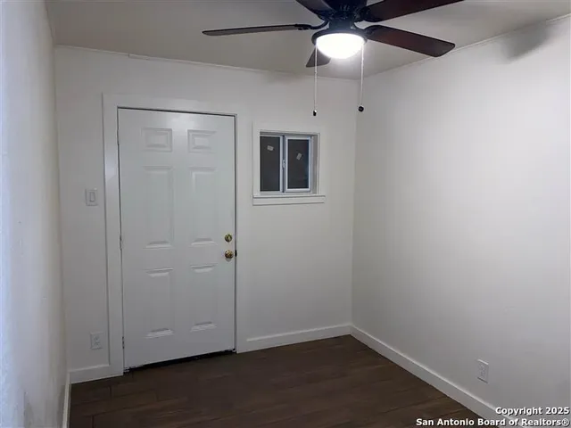 an empty room with wooden floor closet and fan