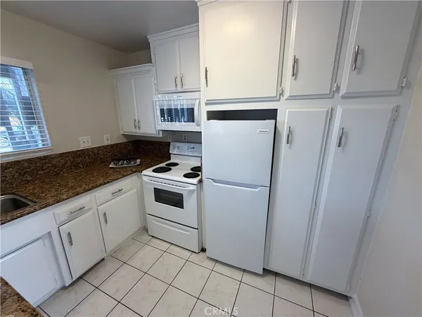 a kitchen with white cabinets and white appliances